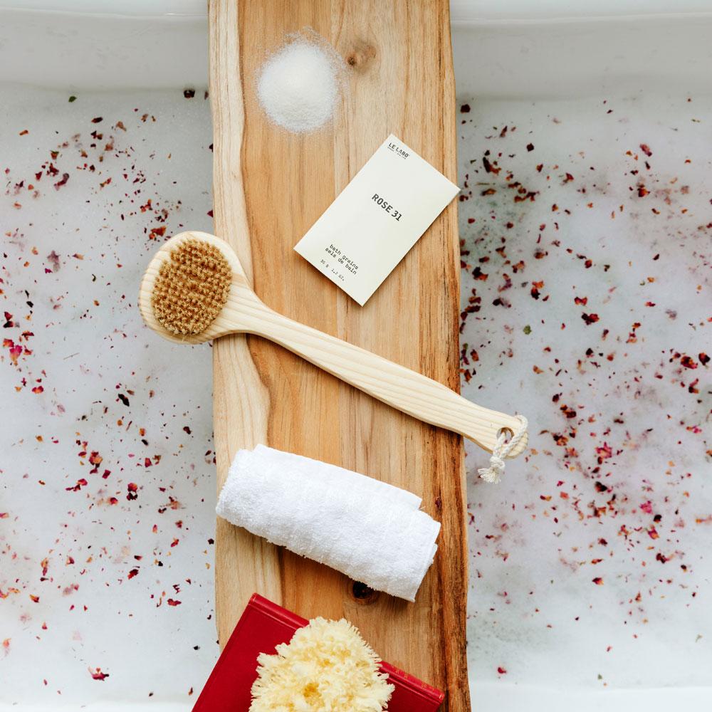 Le Labo Rose 31 Bath Salts on tray in bath tub with rose petals